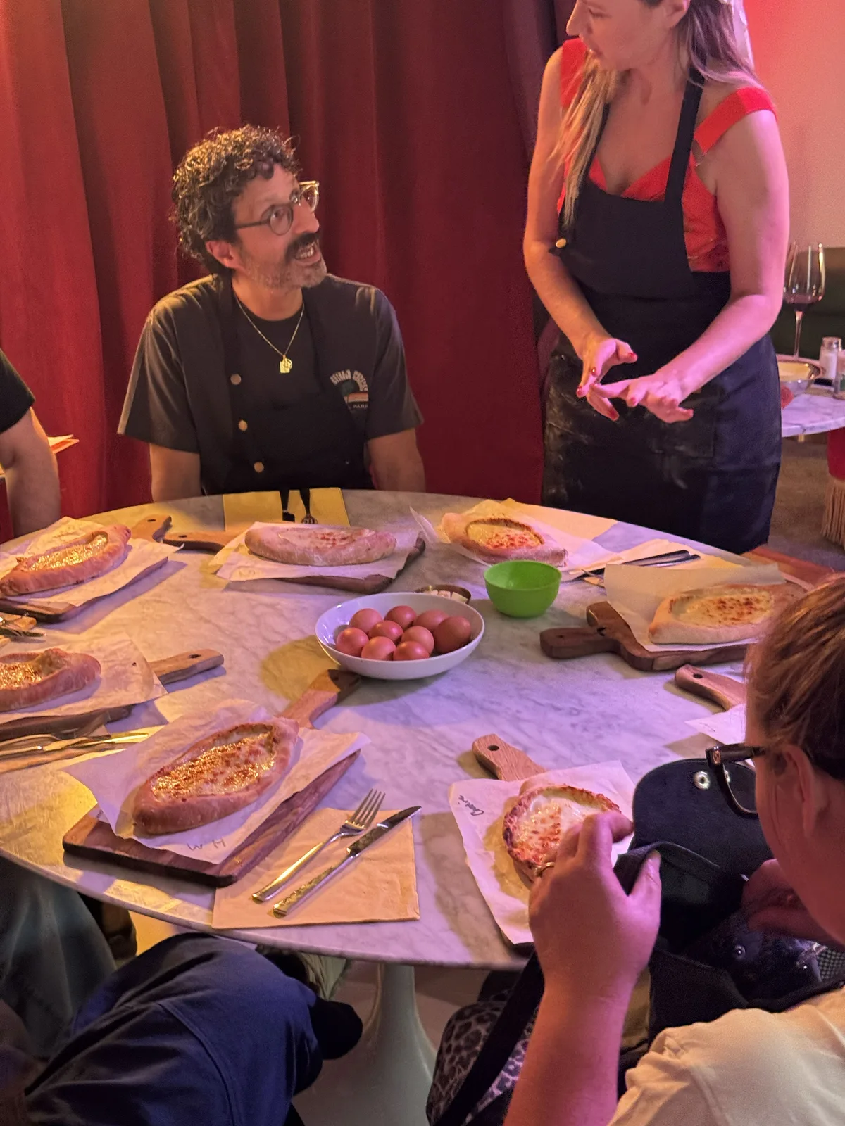 Masha guiding guests around a table of finished adjaruli khachapuri